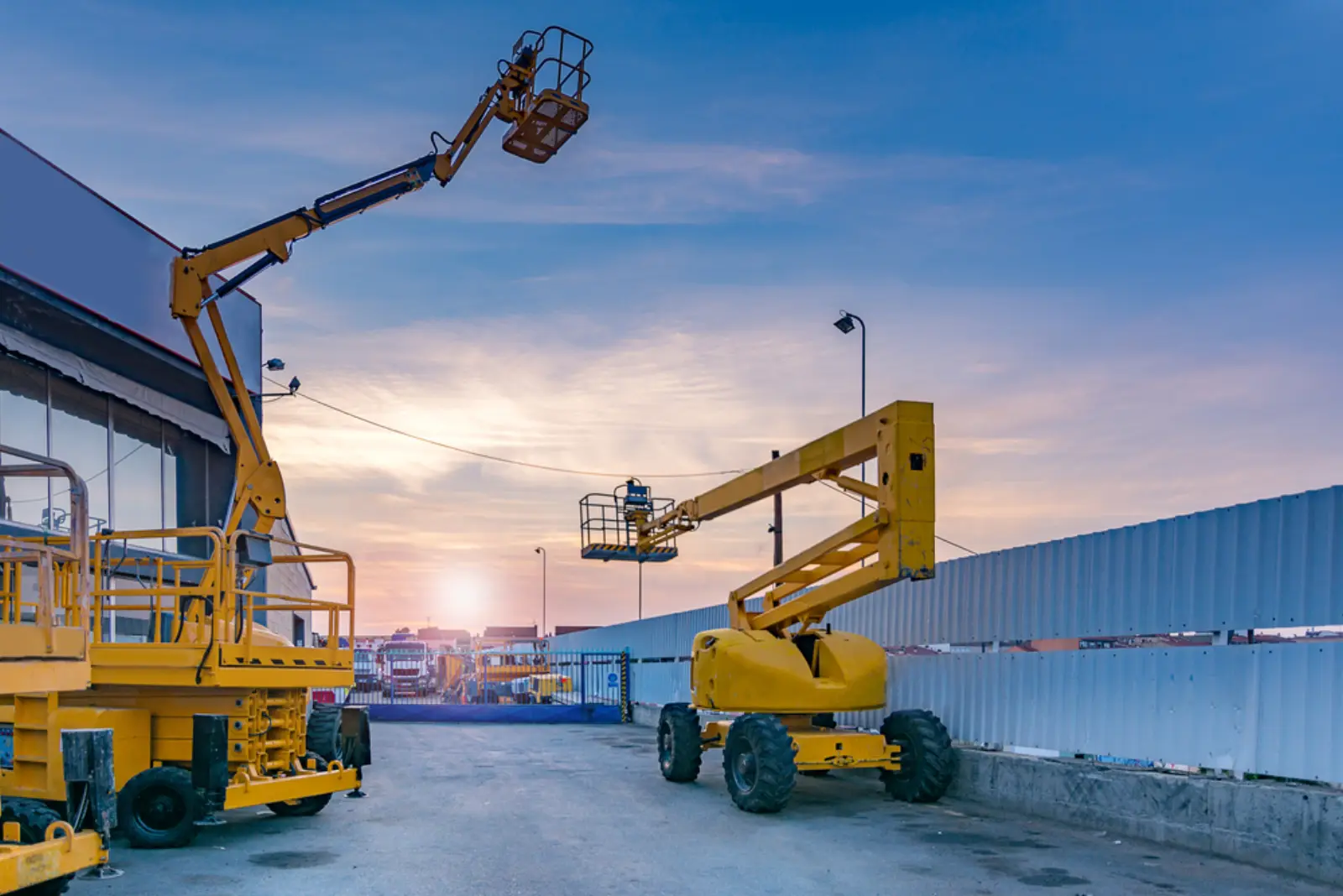 Scissor lift and diesel boom lifts parked on a construction site at sunset, access equipment hire Gosford