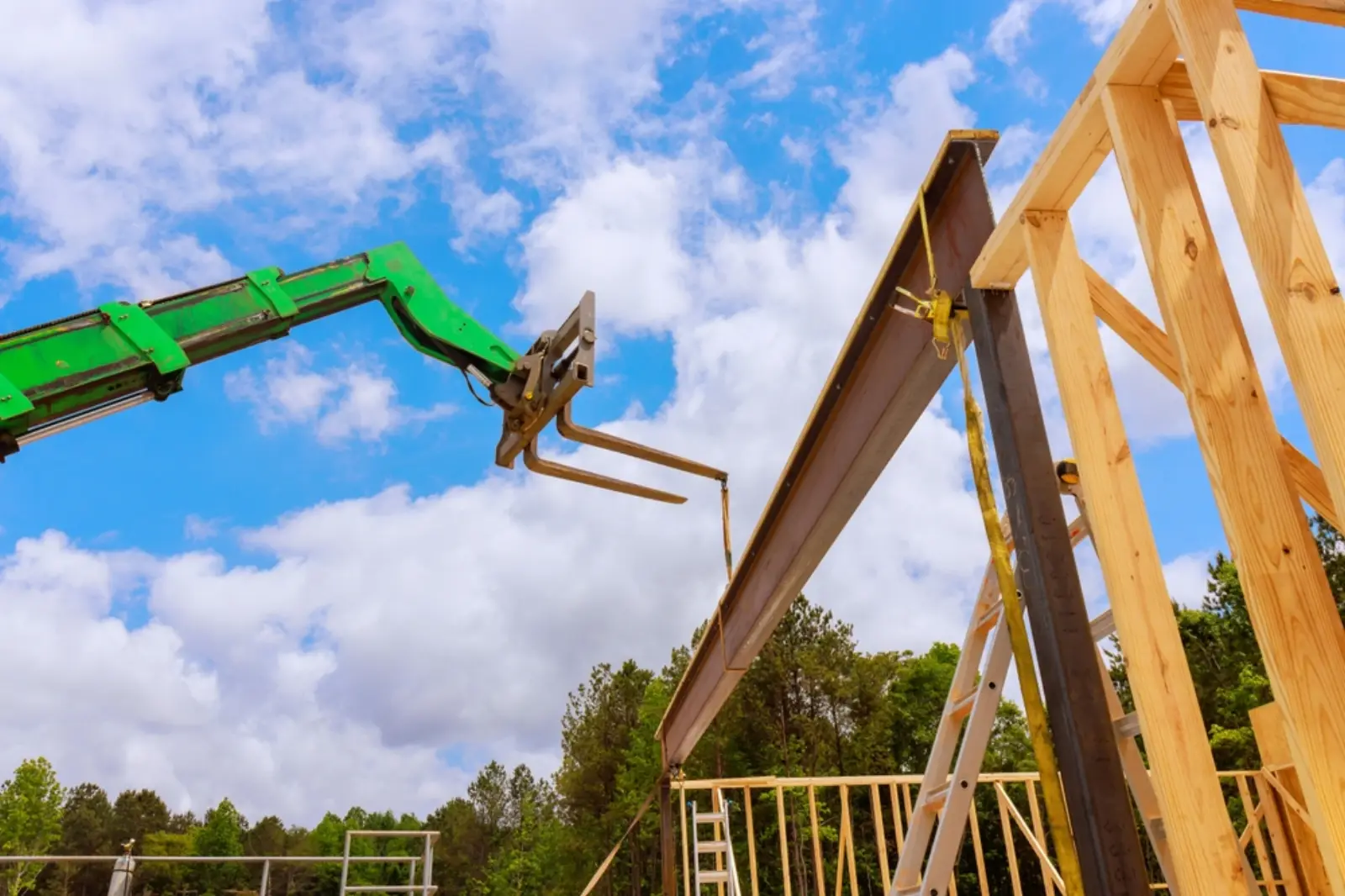 Telehandler lifting a steel beam into place on a timber-framed building site